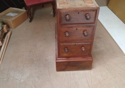 An antique desk pedestal is presented for extra care